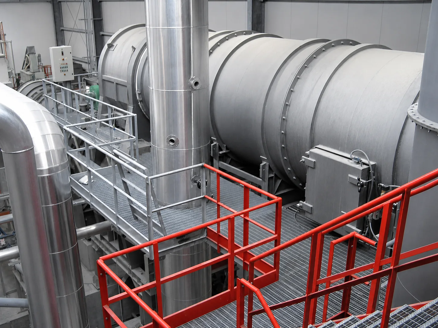 Four rotatif industriel avec conduits et passerelles de maintenance rouges